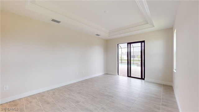 tiled spare room with a tray ceiling