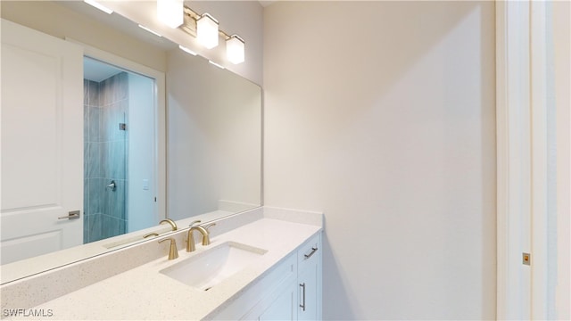 bathroom with a tile shower and vanity