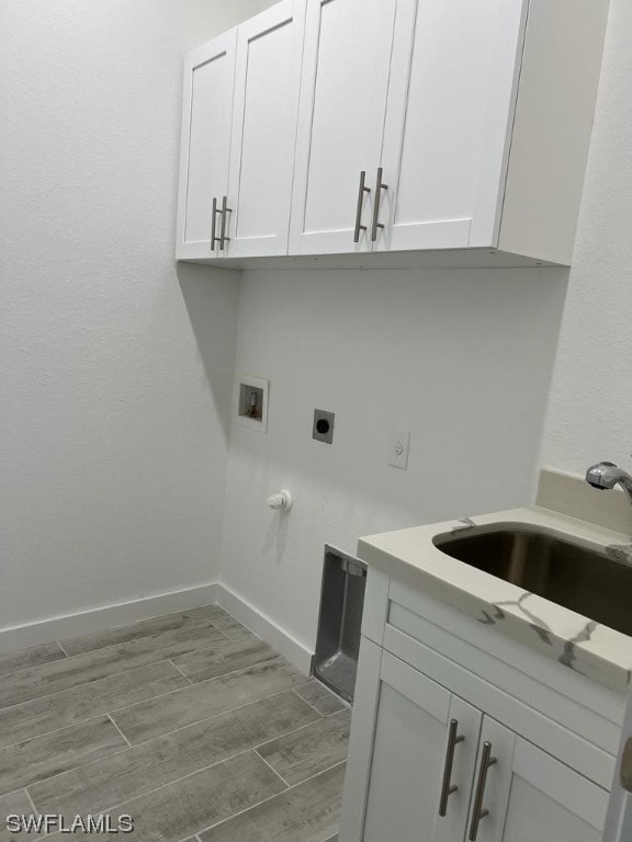 laundry room with electric dryer hookup, washer hookup, cabinets, and wood-type flooring