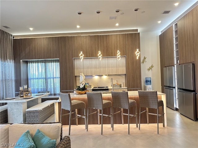 kitchen with decorative light fixtures, wood walls, stainless steel fridge, and a breakfast bar area