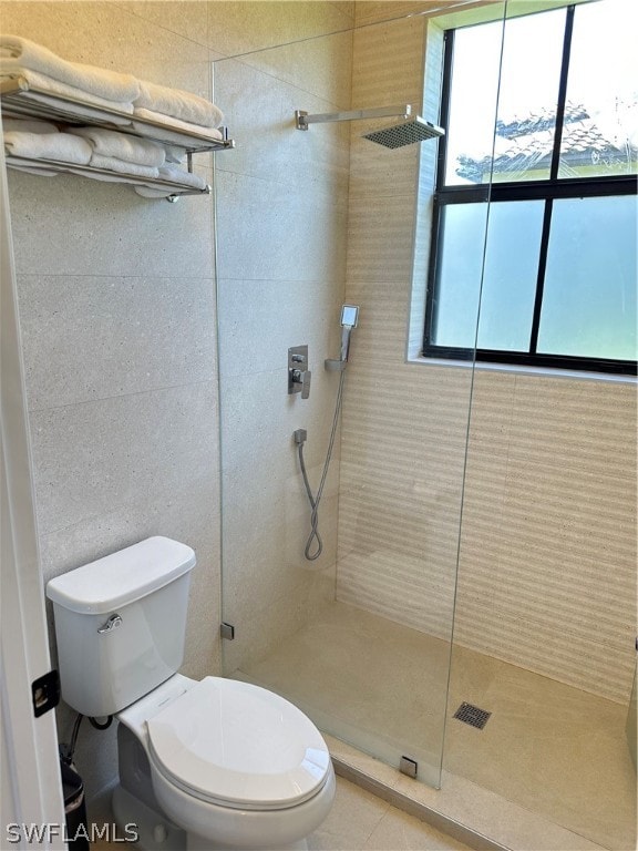 bathroom featuring a wealth of natural light, tiled shower, and toilet