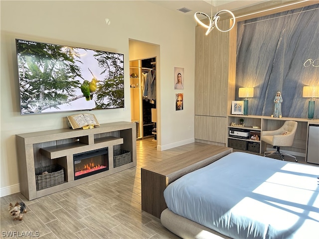 bedroom with wood-type flooring, a notable chandelier, a closet, and a walk in closet