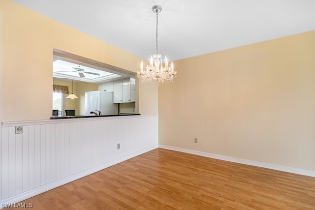 interior space featuring ceiling fan with notable chandelier and light hardwood / wood-style floors