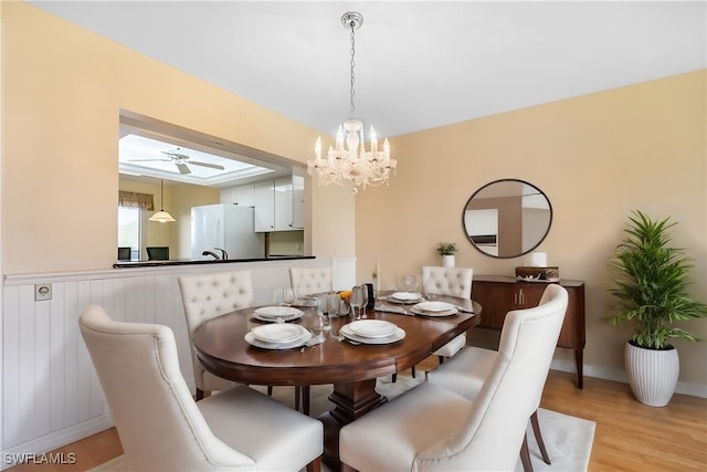 dining space with ceiling fan with notable chandelier and light hardwood / wood-style floors