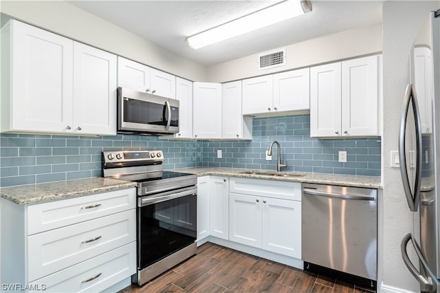 kitchen featuring dark wood-type flooring, sink, stainless steel appliances, white cabinets, and tasteful backsplash