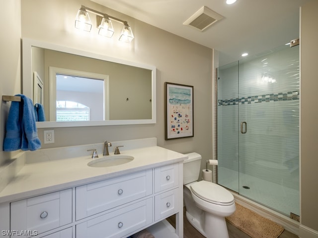 bathroom with a shower with door, toilet, and vanity