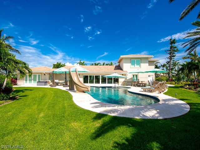 view of pool with a water slide, a yard, and a patio area