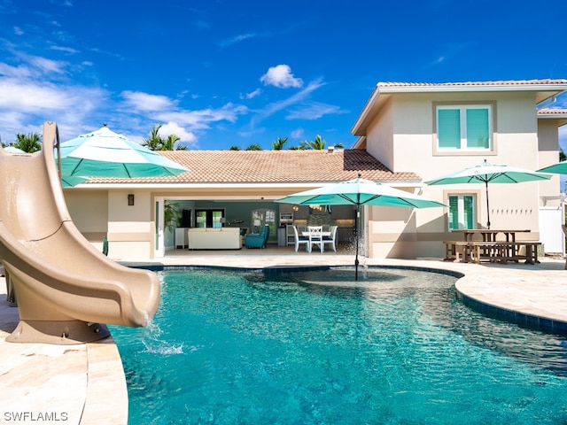 view of swimming pool with a water slide and a patio