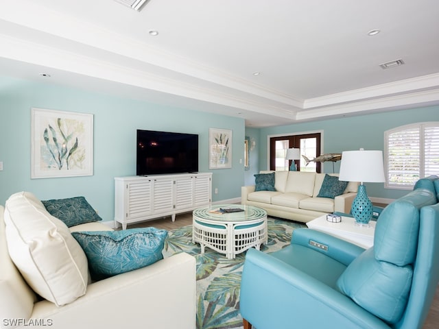 living room with french doors, crown molding, a tray ceiling, and hardwood / wood-style flooring