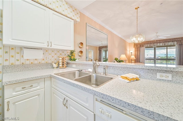 kitchen featuring pendant lighting, ceiling fan with notable chandelier, crown molding, white cabinets, and sink