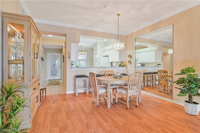 dining room featuring a notable chandelier, ornamental molding, and light hardwood / wood-style floors