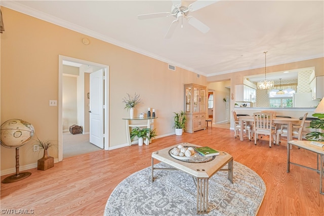 living room featuring ornamental molding, light wood-type flooring, and ceiling fan with notable chandelier