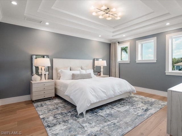 bedroom with hardwood / wood-style flooring and a raised ceiling