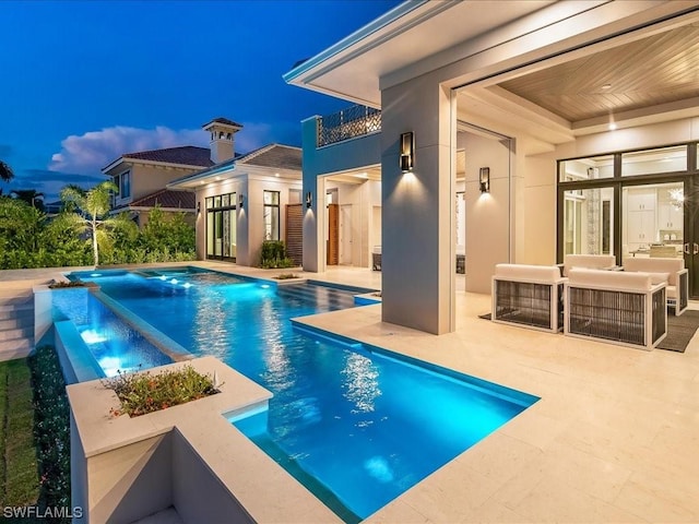 pool at dusk featuring a patio