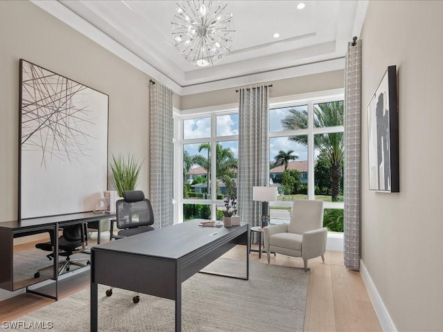 office space with a raised ceiling, hardwood / wood-style floors, and an inviting chandelier