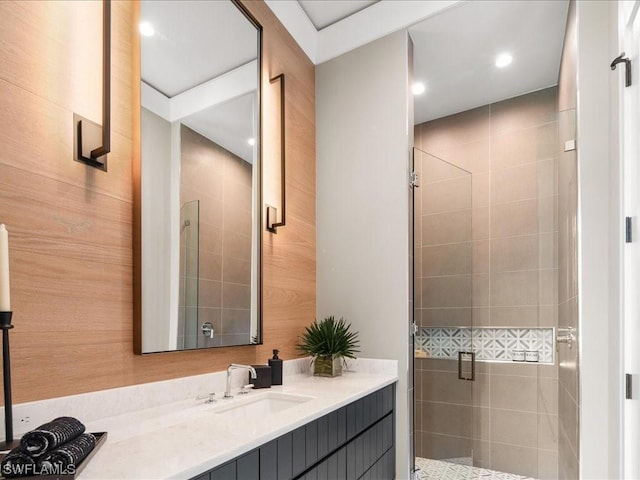 bathroom featuring vanity, a shower with shower door, and wood walls