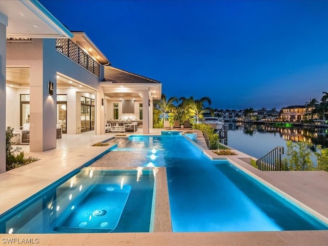 view of swimming pool with an in ground hot tub, a patio, and a water view