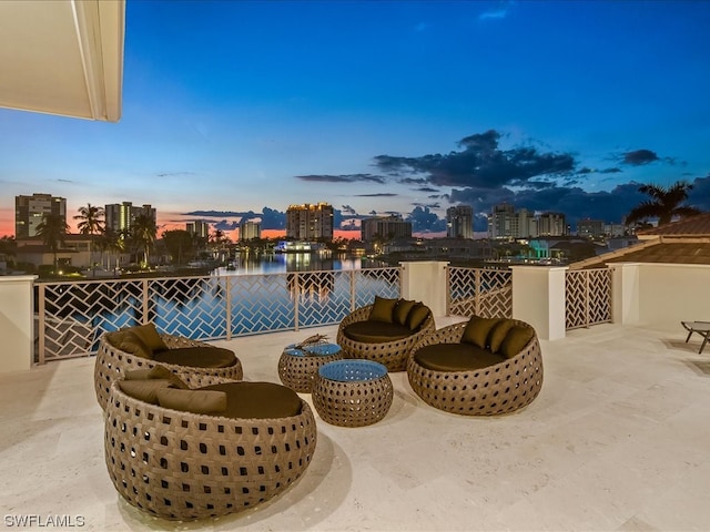 pool at dusk featuring a patio area and a water view