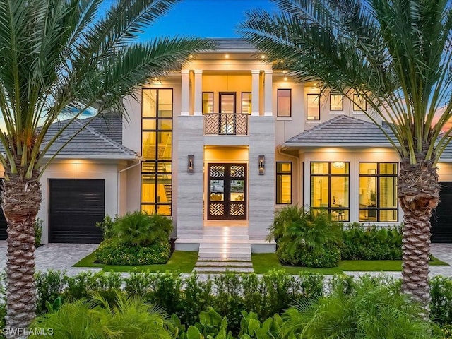 view of front of property featuring a garage, a balcony, and french doors