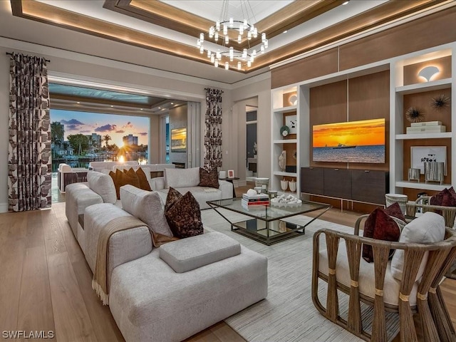 interior space featuring built in shelves, ornamental molding, a raised ceiling, and light hardwood / wood-style flooring