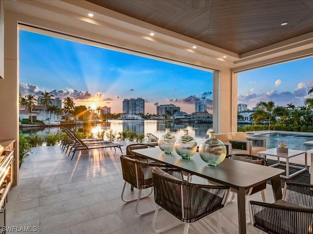 sunroom with wooden ceiling, a raised ceiling, and a water view