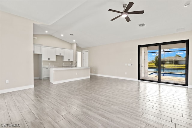 unfurnished living room with lofted ceiling, light wood-style flooring, visible vents, baseboards, and a ceiling fan