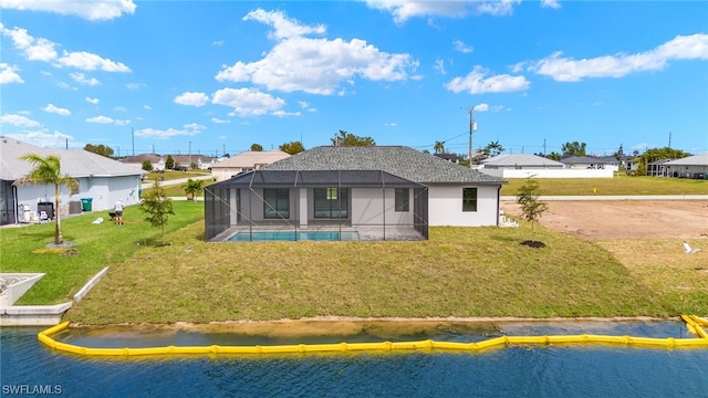 back of house with a lanai, a water view, an outdoor pool, and a yard