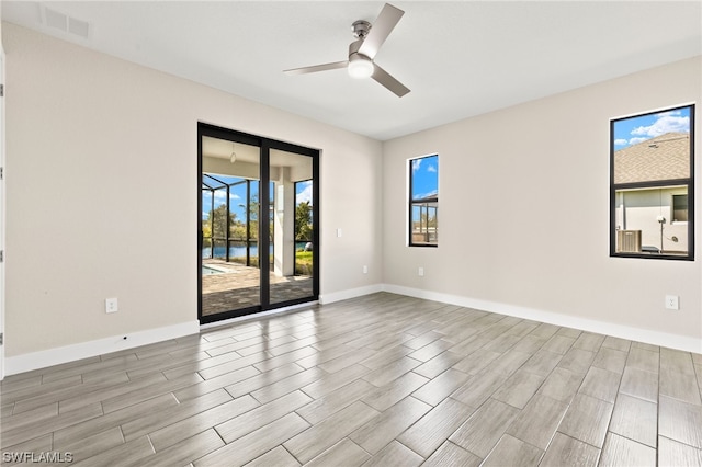 empty room with a ceiling fan, wood tiled floor, visible vents, and baseboards