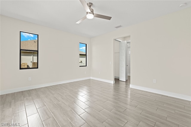 spare room featuring visible vents, wood finish floors, a ceiling fan, and baseboards