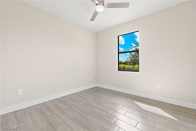 spare room featuring a ceiling fan, wood tiled floor, and baseboards