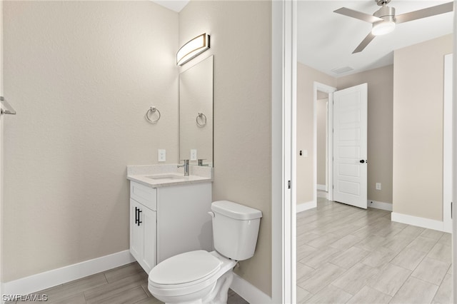 bathroom with baseboards, a ceiling fan, toilet, vanity, and wood finish floors