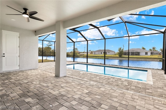 view of pool with glass enclosure, a water view, a ceiling fan, a residential view, and a patio area