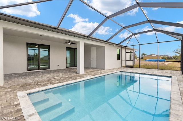 outdoor pool with glass enclosure, a ceiling fan, and a patio