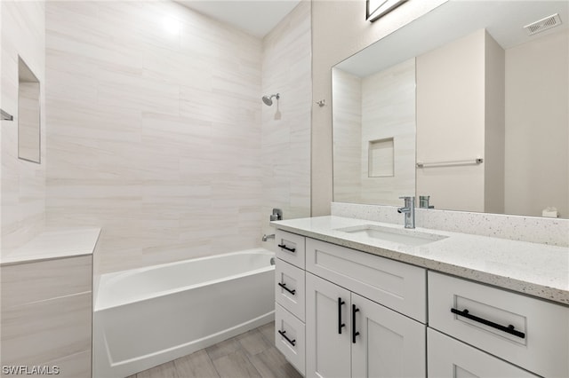 bathroom with tiled shower / bath combo, vanity, and hardwood / wood-style floors