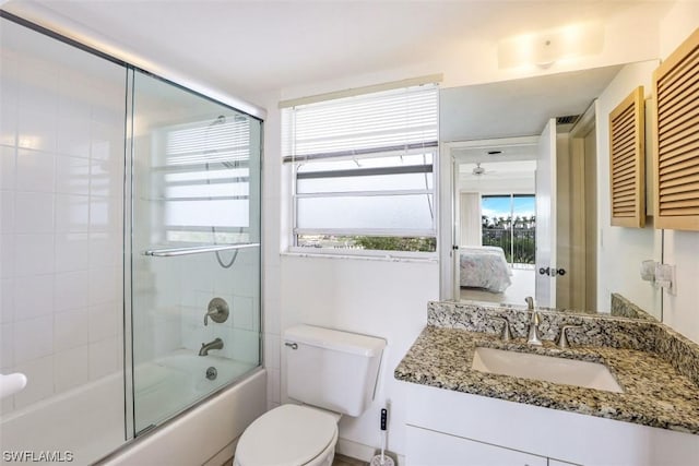 bathroom with ceiling fan, toilet, vanity, combined bath / shower with glass door, and ensuite bath