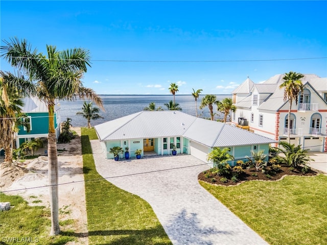 view of front of house featuring a balcony, a front lawn, and a water view