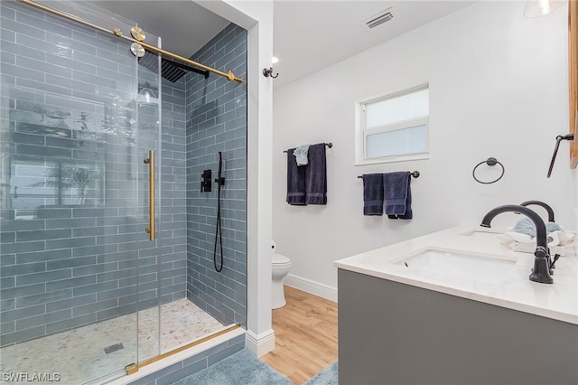 bathroom with toilet, vanity, an enclosed shower, and wood-type flooring