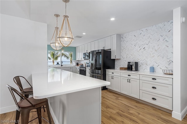 kitchen with pendant lighting, light hardwood / wood-style floors, tasteful backsplash, a breakfast bar area, and white cabinetry