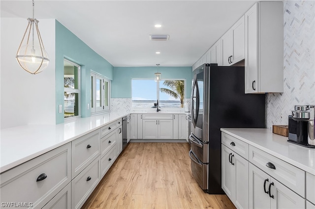 kitchen featuring backsplash, light hardwood / wood-style flooring, a healthy amount of sunlight, and decorative light fixtures