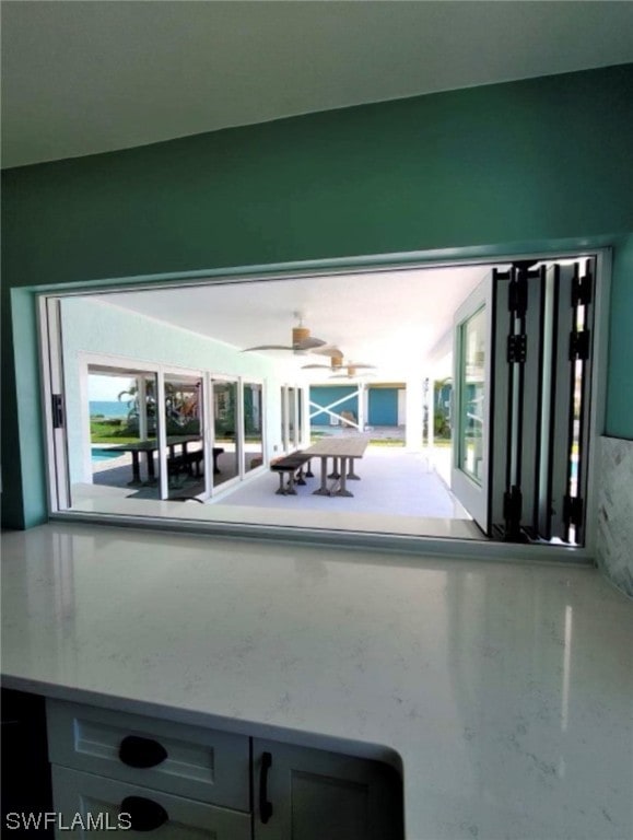 exterior space featuring ceiling fan and light stone counters