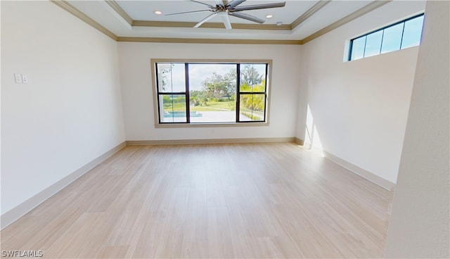 unfurnished room featuring crown molding, ceiling fan, a tray ceiling, and light hardwood / wood-style flooring