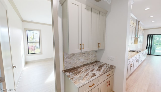 kitchen with white cabinets, crown molding, backsplash, and light stone counters