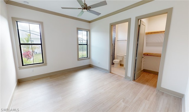 unfurnished bedroom with a closet, a walk in closet, ceiling fan, connected bathroom, and crown molding