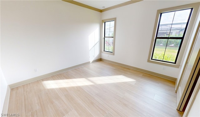 unfurnished room featuring a healthy amount of sunlight, ornamental molding, and light hardwood / wood-style flooring