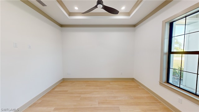 unfurnished room featuring light hardwood / wood-style floors, a tray ceiling, and ceiling fan