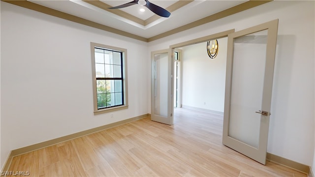 unfurnished room with a raised ceiling, light hardwood / wood-style floors, and ceiling fan