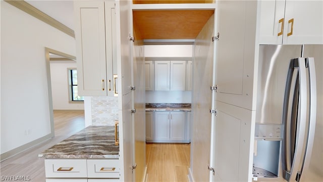 kitchen featuring white cabinets, stone countertops, light wood-type flooring, and stainless steel refrigerator with ice dispenser