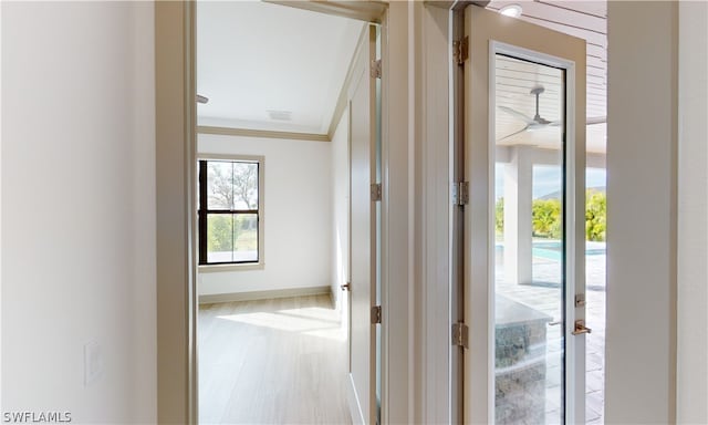 hallway featuring french doors, ornamental molding, and light wood-type flooring