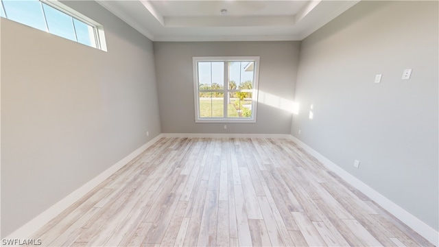 unfurnished room featuring a tray ceiling, crown molding, and light hardwood / wood-style flooring