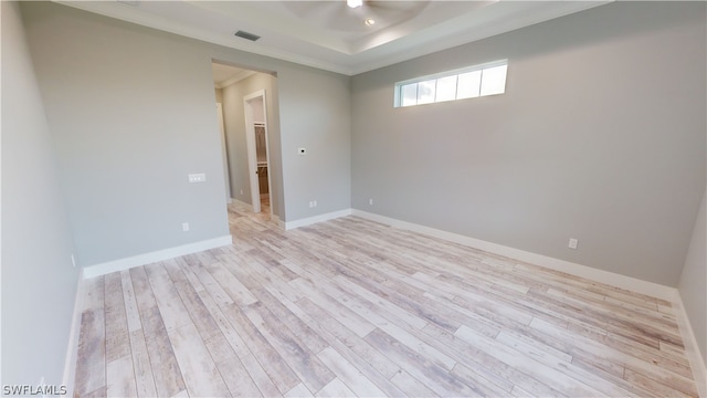 empty room featuring ornamental molding, light hardwood / wood-style floors, and a tray ceiling